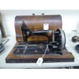 An early 20thC manual sewing machine with floral on black decoration and a wooden dome cover