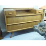 A 1970s teak finished dressing table with a drop down centre open shelf,