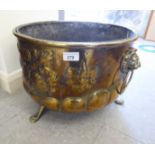 An early 20thC brass coal bin with twin lion mask handles and embossed ornament,
