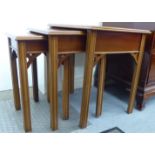 A nesting set of three modern yewwood occasional tables, raised on square legs largest 22''h 22.