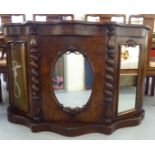 A late Victorian walnut serpentine front chiffonier with a central mirrored door,