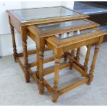 A nesting set of three stained beech occasional tables, each with an inset glass top,