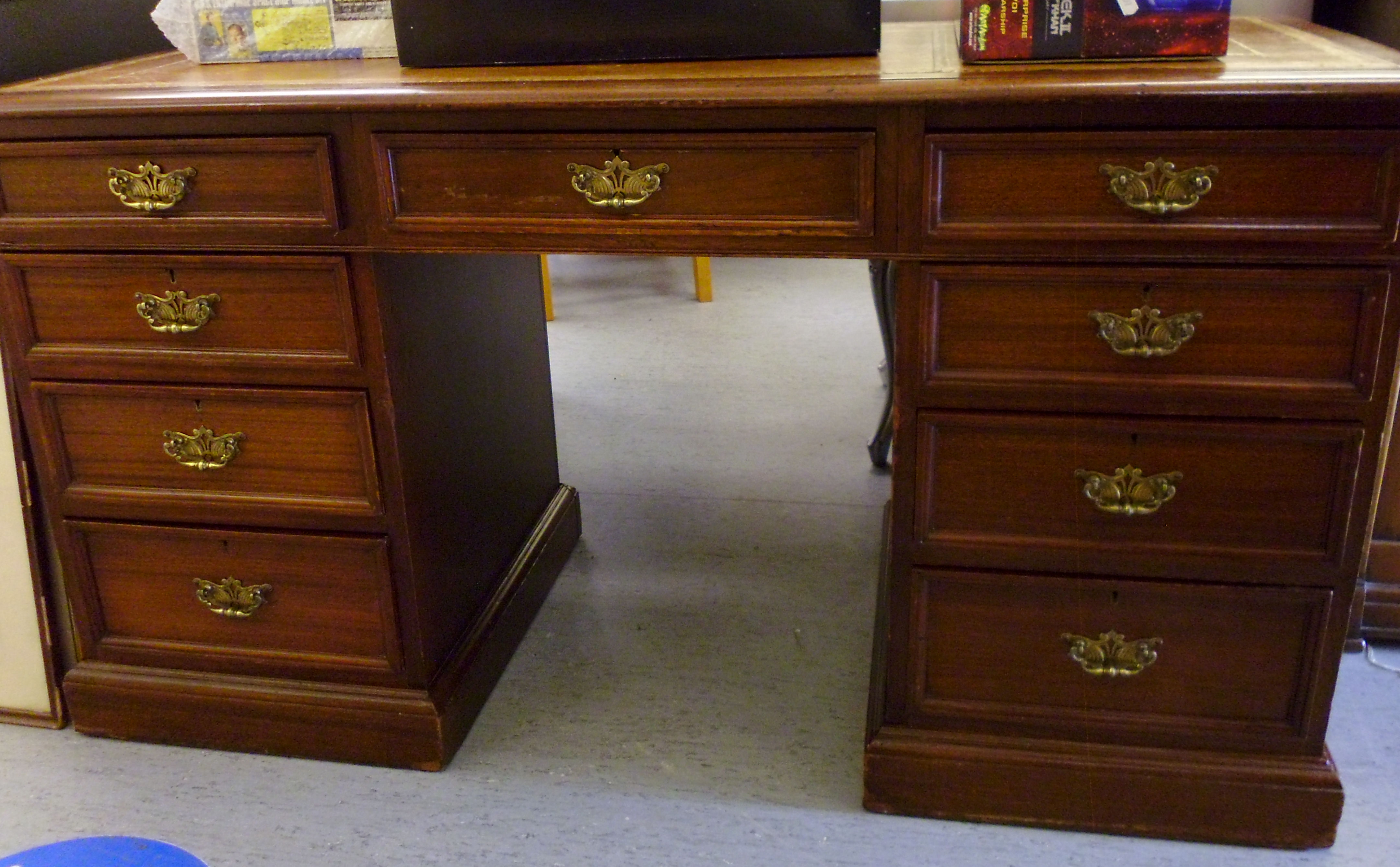 An early 20thC mahogany desk, the top set with a tooled brown hide scriber,