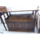 A 1930s stained oak monk's bench with a hinged seat over a panelled front,