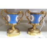 A pair of early 20thC French gilt metal and painted porcelain twin handled,