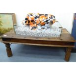 A modern painted soapstone sculpture of seven stylised fish, seated upon a bed of rocks,