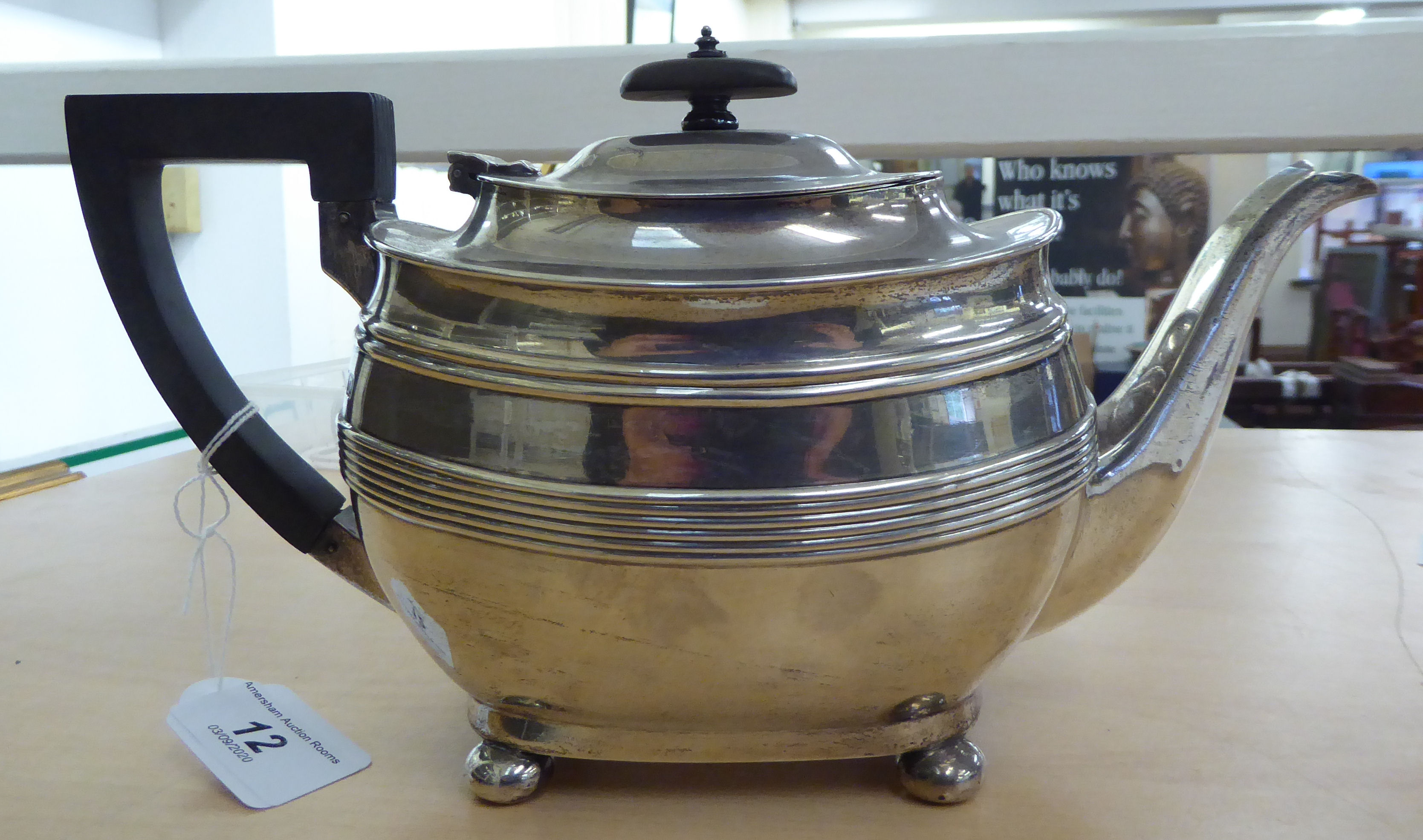 A Georgian style silver teapot of oval, bulbous form with embossed wire ornament, a swept spout,