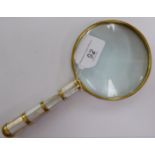 A handheld brass and mother-of-pearl moulded magnifying glass OS10