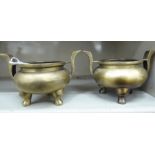 A pair of Oriental cast and patinated bronze censers, the bulbous bowls with opposing,