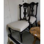 A pair of Edwardian mahogany framed carved splat back nursing chairs, the cream patterned,