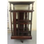 An early 20thC mahogany revolving bookcase, the two open tiers with slatted sides,