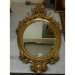 A modern mirror, the oval bevelled plate set in a Regency design,