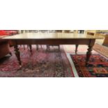 A late Victorian mahogany dining table, the top with round corners, raised on ring turned,
