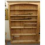 A modern honey coloured pine open front bookcase with a level cornice,