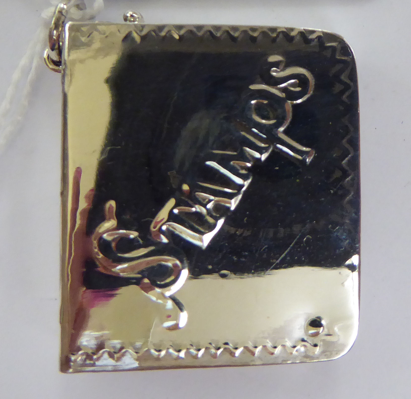 A silver postage stamp box, fashioned as a book with a rotating cover,