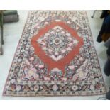 A Persian rug with a central floral patterned diamond shaped motif,