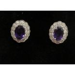 A pair of earrings, claw set with an oval faceted amethyst,