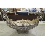 A silver coloured metal table centrepiece of navette form with opposing, high, scrolled handles,