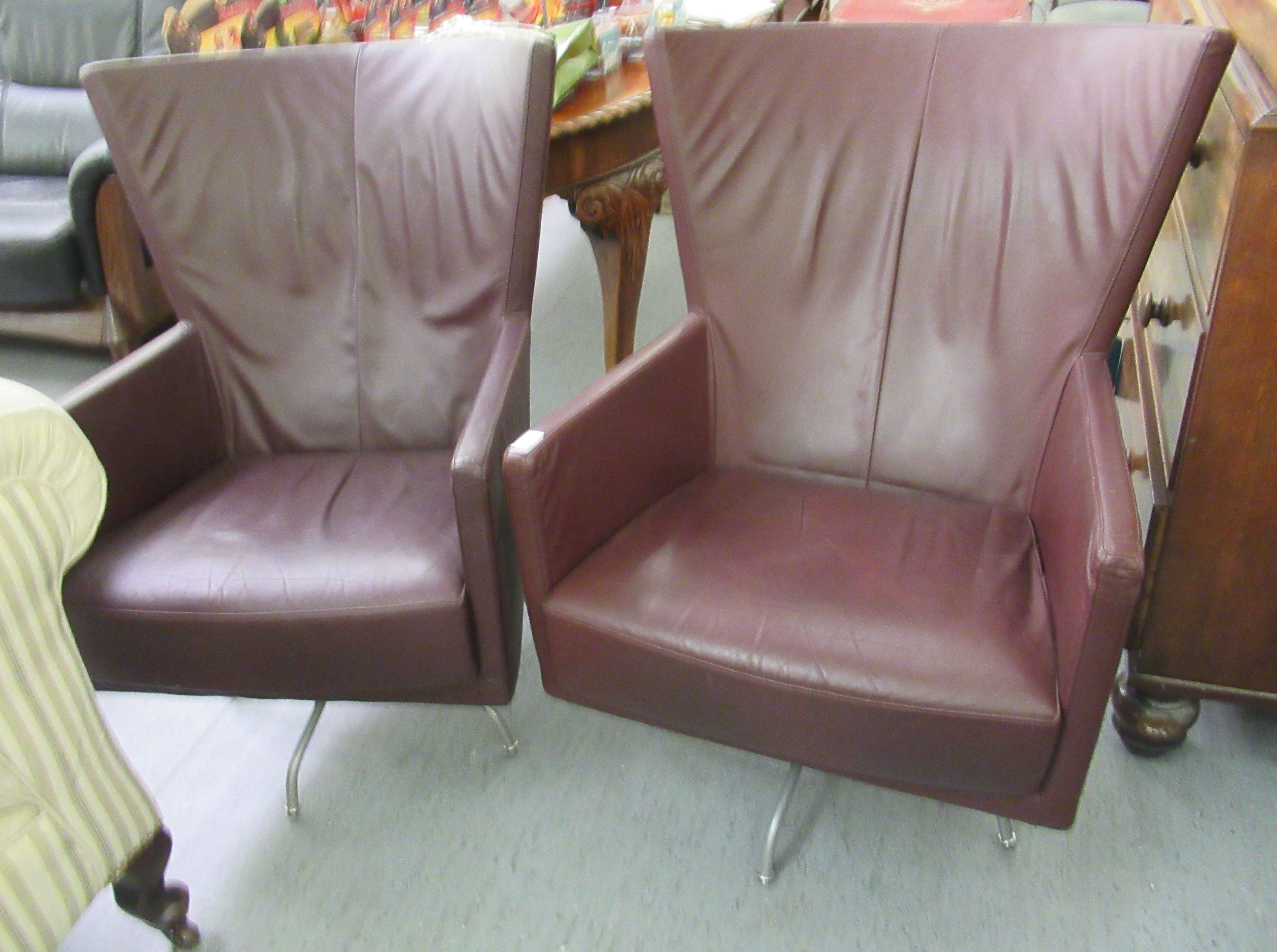 A pair of modern 'vintage' style wingback chairs, having enclosed arms,