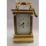 A mid 20thC miniature lacquered brass mantle timepiece with a folding top handle and bevelled glass