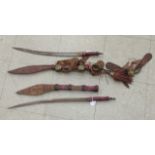 Two similar African tribal swords with red hide clad handles and scabbards the blades 19''L
