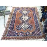 A Persian rug, decorated with three central diamond shaped motifs,