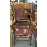 An early 20thC spindle back open arm chair with a solid seat, raised on turned,
