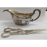 A silver sauce boat with a flared cup and double C-scrolled handle,