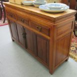 A 20thC Chinese fruitwood dresser base with three frieze drawers, over four panelled doors,