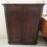A George III oak hanging corner cabinet with a pair of panelled doors,