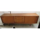 A early 1970s teak sideboard with a central bank of four drawers, behind two sliding doors,
