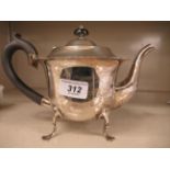 A silver teapot of cauldron design with a decoratively cut, flared border,