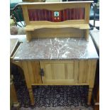 An Edwardian walnut washstand with a tiled back and marble top, over a door,