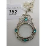 A silver framed magnifying glass pendant, set with blue topaz,