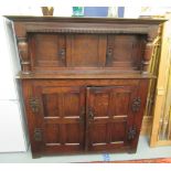 An early 20thC stained oak court cupboard with two doors beside pillar supports,