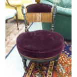 An Edwardian ebonised showwood framed nursing chair with a burgundy coloured fabric upholstered