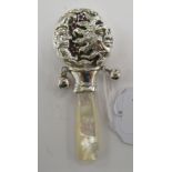 A baby's silver rattle, featuring sun and moon faces and two bells,