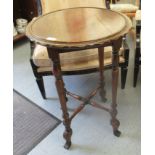 A 1920s oak occasional table with a wavy edge, raised on slender,
