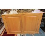 A modern light oak cabinet with a panelled front,