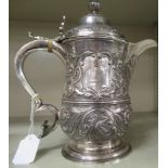 A silver jug of waisted baluster form, having a hollow C-scrolled handle, covered spout,