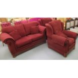 A three piece suite with level backs and scrolled arms, upholstered in maroon fabric,