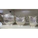 A three piece silver tea set of oval, demi-reeded form, the teapot having a swept spout,