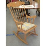 A modern beech framed, spindled back rocking chair with scrolled arms,