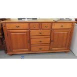 A modern waxed pine dresser, comprising an arrangement of cupboards and drawers,