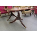 A Regency style mahogany dining table with double D-ends and a central leaf, raised on twin,