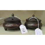 A pair of Oriental cast and patinated bronze censers, having pierced covers and finials,