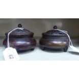 A pair of Oriental cast and patinated bronze censers, having pierced covers and finials,