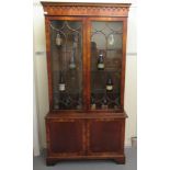 A Sheraton inspired two part mahogany finished cabinet bookcase with a dentil and pendant moulded