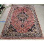 A Persian rug, decorated with stylised flora and other designs,