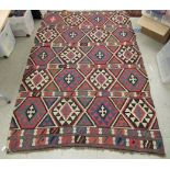 A Caucasian Kelim rug, decorated with repeating geometric designs,